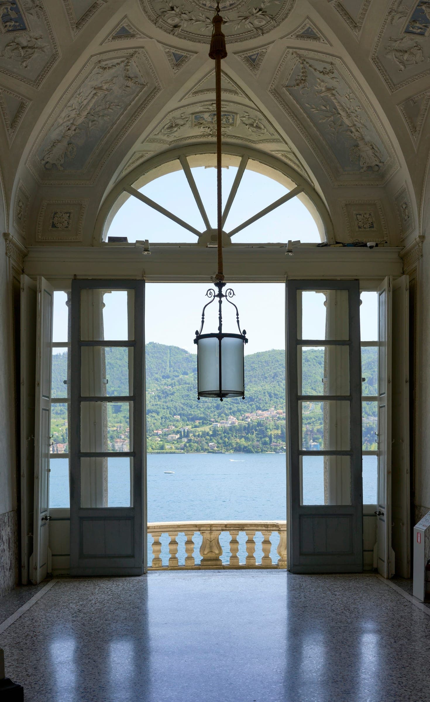 Arched glazed doors and a hanging lantern, the lake beyond