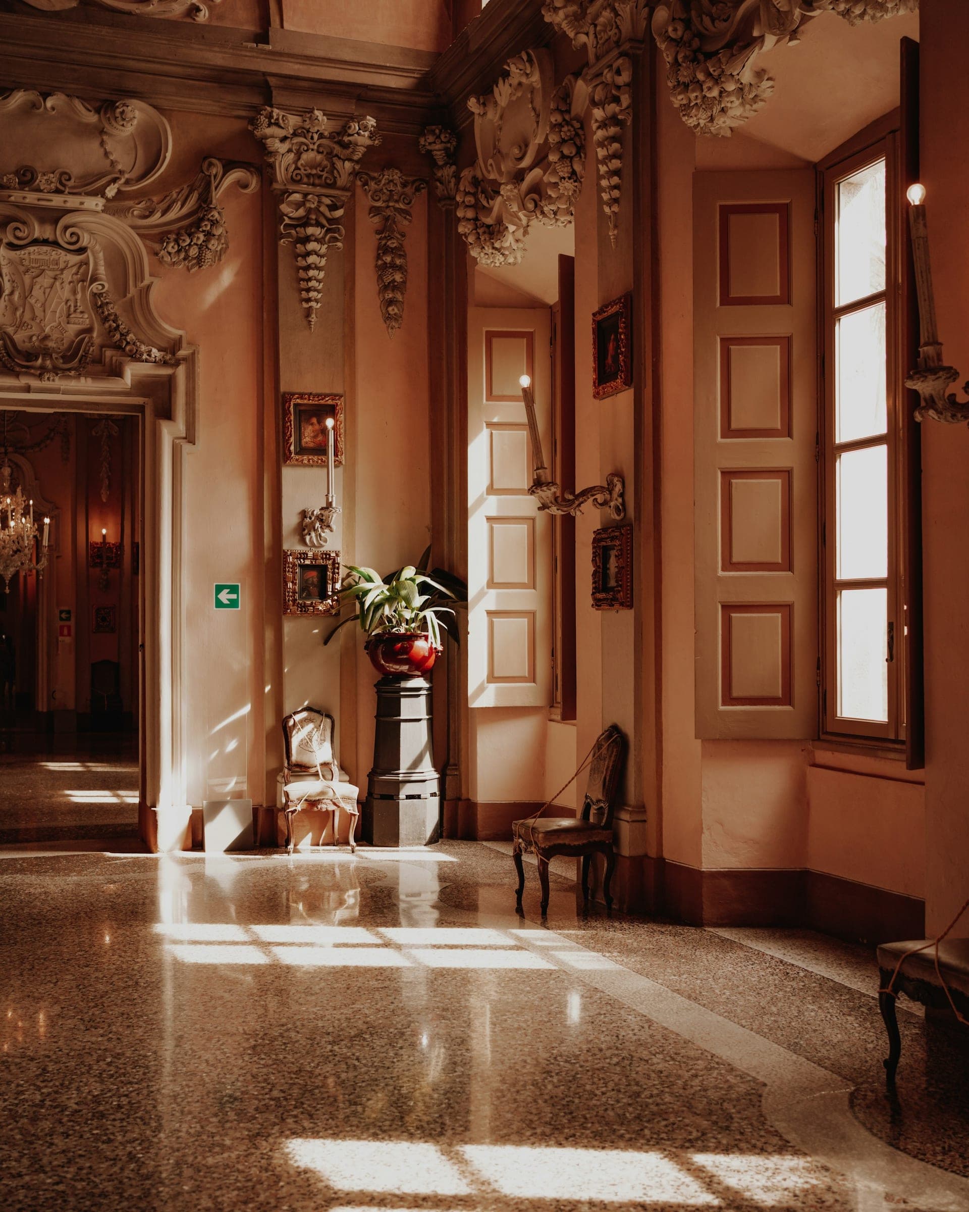 A pale pink stucco hall with a terrazzo floor in patches of sun