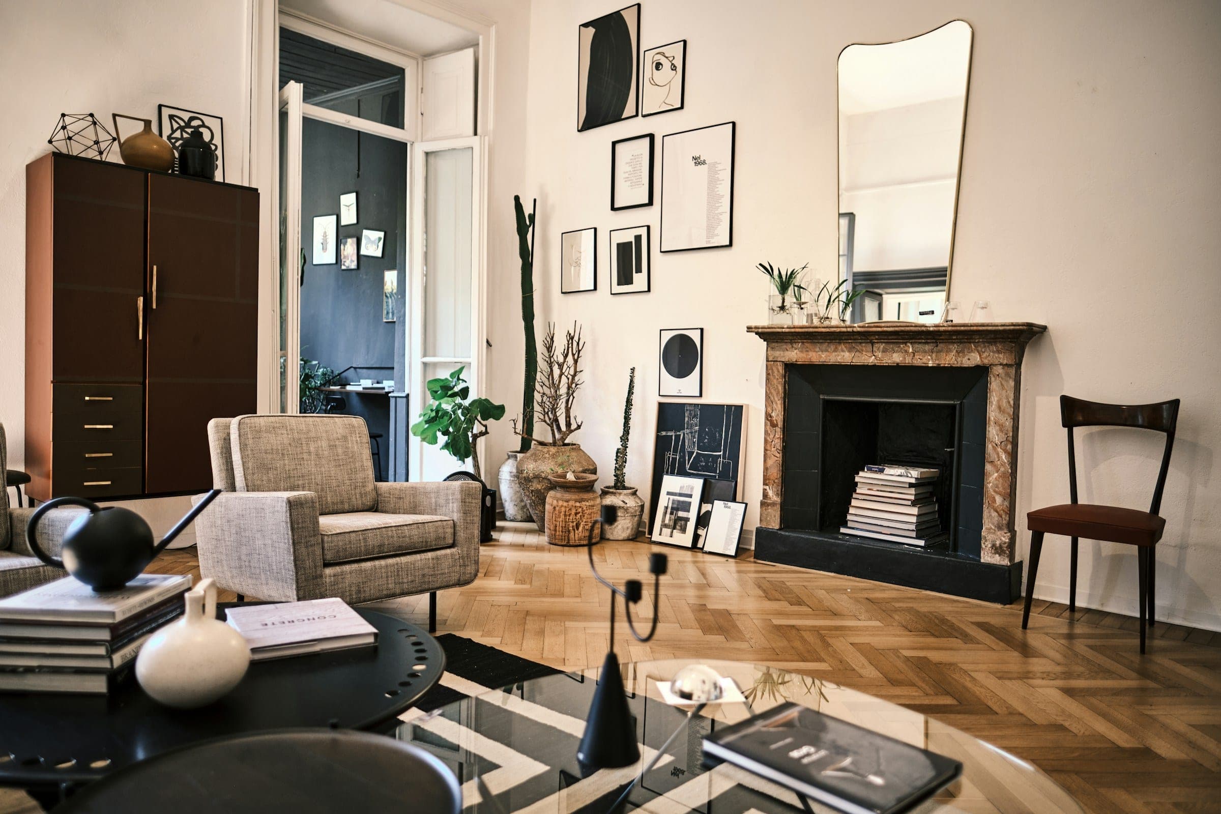 A sitting room with herringbone parquet, a marble fireplace and a mirror